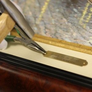 Close up of pliers applying a brass nameplate